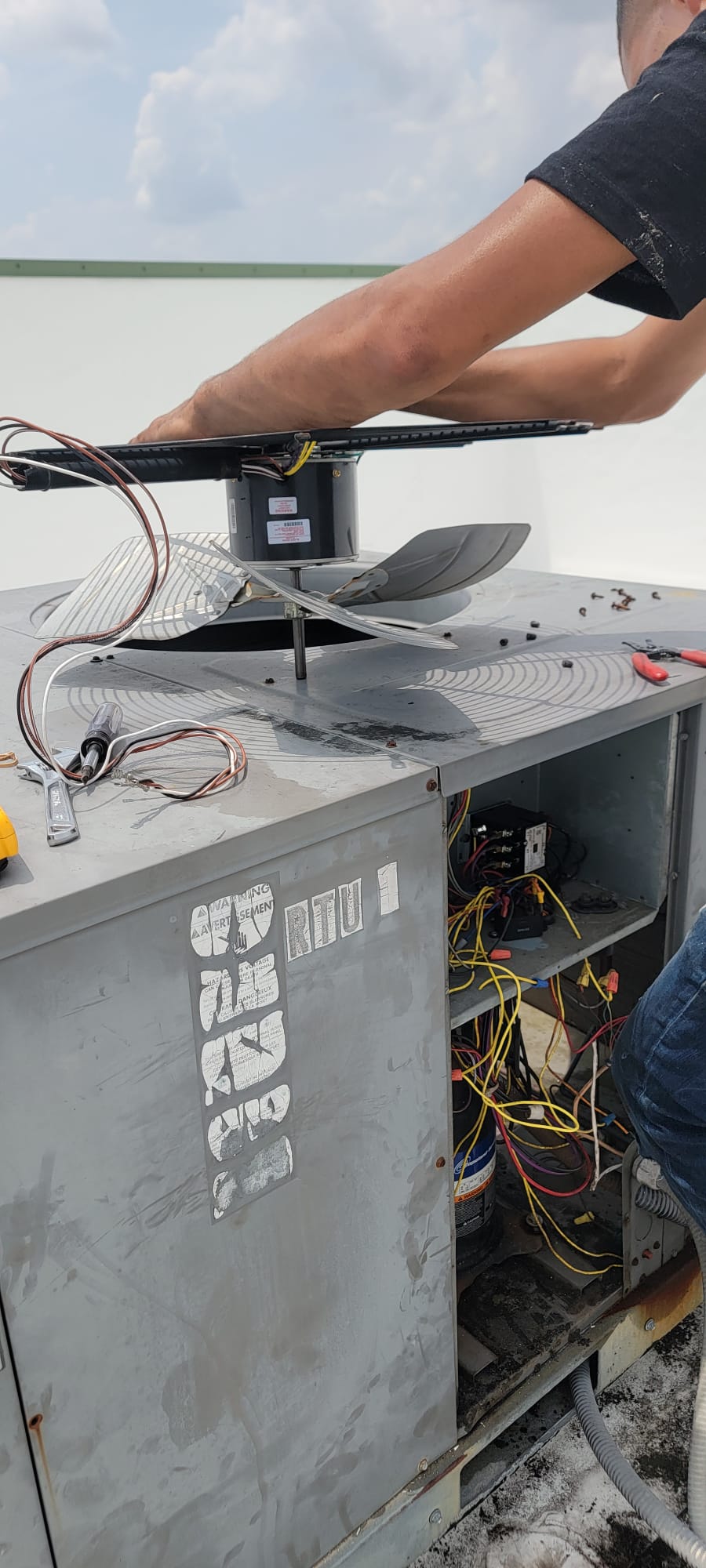 HVAC technician performing A/C maintenance on a rooftop unit